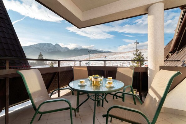 A cozy balcony with a table and chairs, offering a breathtaking panoramic view of the mountains.