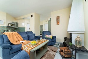 A spacious living area featuring blue sofas, a warm fireplace, and traditional decor elements.