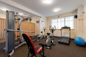 A small gym equipped with machines like a treadmill and weights, set in a bright and organized space.