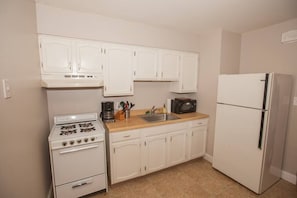 Fully stocked kitchen, coffee maker, range, microwave and full size fridge. Not Pictured is a kitchen table 