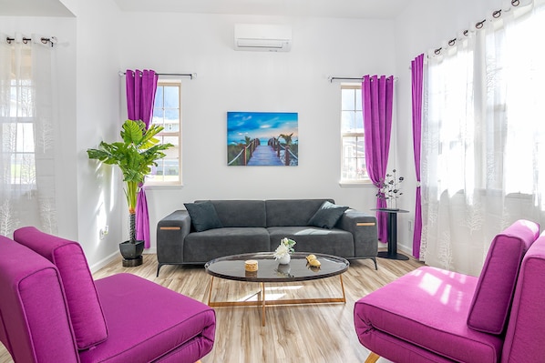 Colorful, sunlit living room with bold seating and cozy modern vibes!