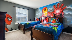 Action-packed superhero bedroom with twin beds, bold murals, and fun Marvel-themed bedding.