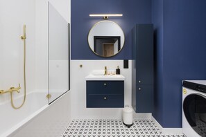 A bathroom featuring a blue-and-white color scheme, a circular mirror, and a minimalist sink area.