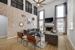 With high vaulted ceilings and a brick accent wall, this airy, comfortable living room has plenty of seating for you to relax and make yourself at home.