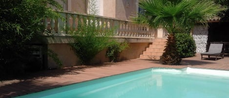 l'espace piscine avec douche extérieure et terrasses carrelée avec store et bois