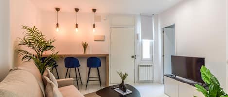 Main view of the living room space with a high dining table in the background