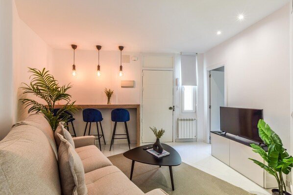 Main view of the living room space with a high dining table in the background