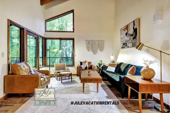 Enjoy the view of the pine trees while relaxing in the stylishly decorated living room with a vaulted ceiling and exposed beams.