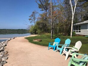 Sandy beach with seating and bonfire pit.