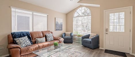 Living room with large 4k Smart TV on wall.  Both sides of sofa recline and blue chairs pivot.