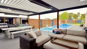 An expansive alfresco dining area thoughtfully designed for entertaining, featuring an outdoor kitchen, cozy lounging spaces, and dining table.
