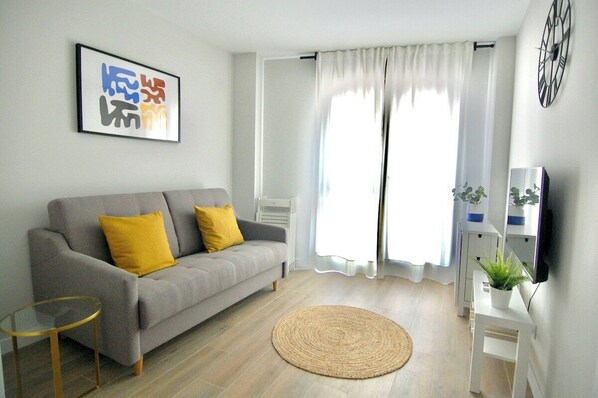 Salón comedor con gran ventanal por el que entra mucha luz natural / Living room with a large lookout window which lets plenty of sunlight in.