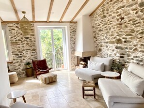 Living room with exposed stone walls, exposed timber ceiling, travertine floors