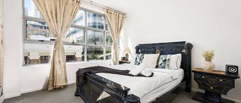 A large bedroom with a queen sized bed & plush pillows.