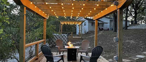 Fire pit under lighted pergola.