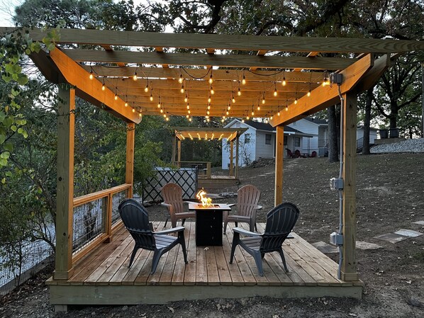 Fire pit under lighted pergola.