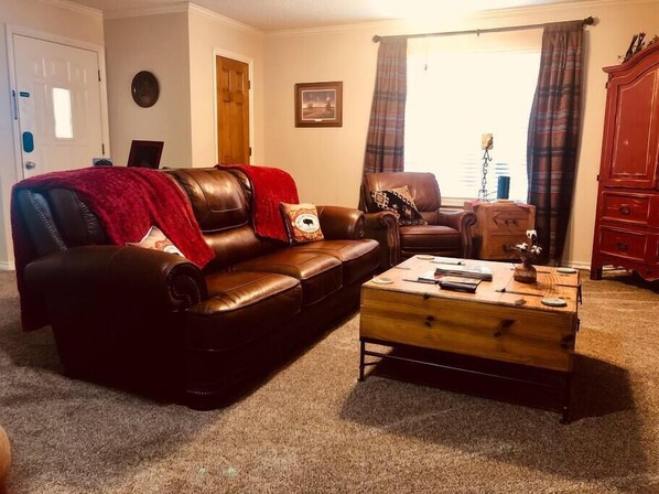 Living area with leather couch and recliners. 