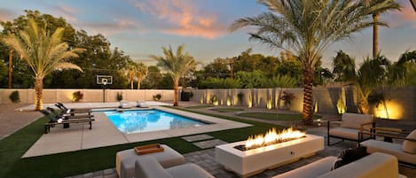Cuddle up with friends and family in this backyard oasis with a fire pit, comfortable couches, and swaying palm trees.