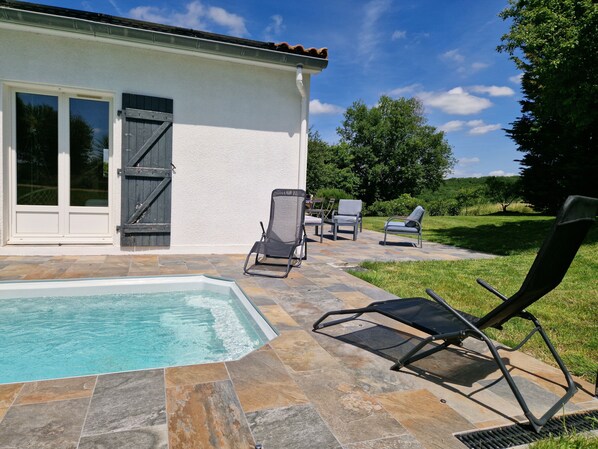 Sublime extérieur avec piscine chauffée, végétation autour de la terrasse.