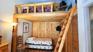 The main level bedroom features a twin bed and twin trundle bed with a ladder leading up to the loft space where you will find a futon for extra sleeping space all surrounded by lovely woodwork.