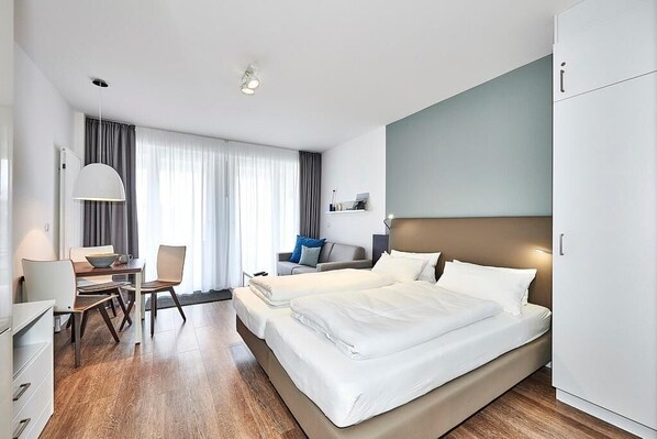 Wohn-, Ess-, Schlafbereich mit Couch, Esstisch und Sitzgelegenheit und Doppelbett