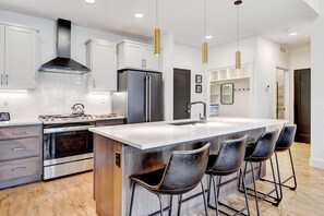 Sleek White Slab Counters Shine Against The Two-Toned Custom Wood Cabinetry