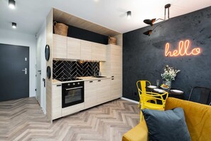 A stylish hallway with a "hello" neon sign, yellow chairs, and dark accent walls.