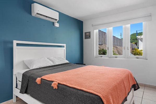 bright bedroom with queen sized bed, blue wall decor, air conditioner, window with pool views, nice comforter and soft bed linens, cabinets and hangers, long wall mirror