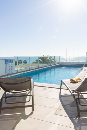 Sun loungers and beach towels around the pool with sea view