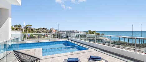 sunloungers and beach towels around the pool and a great sea view