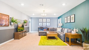 Bright and spacious family room with cozy sectional, large TV, stylish decor, and a dedicated workspace.