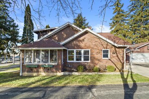 Side view of Red Brick Home with seasonal porch with outdoor lounging furniture