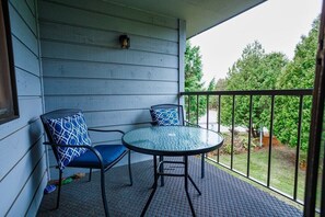 Private balcony includes two chairs, a table and views of a beautiful garden