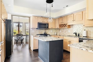 Fully appointed kitchen with gas stove, microwave, dish washer, ample dishware.