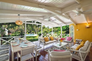 The main deck has a tropical wooden floor and looks out to the garden & pool