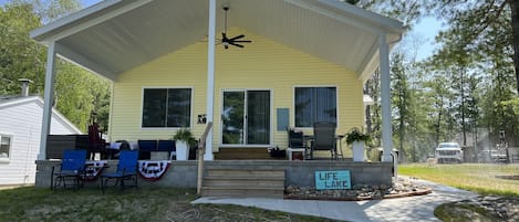 front which looks at the lake, porch with ceiling fan, sectional and table