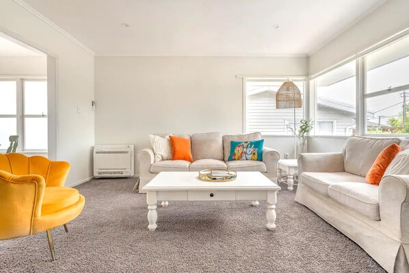 Main living area with two comfy couch’s, a single chair and air con
