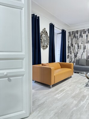 The living room is spacious and sunny, with magnificent balconies overlooking the street, two sofa beds and a television.
