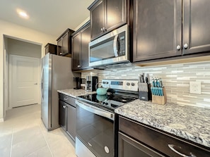 - Stainless steel appliances & granite counters make cooking feel like a breeze
- Stocked with a coffee maker, knife block, & all the essentials for easy meal prep
- Modern backsplash & rich cabinetry bring both style & function to your kitchen experience