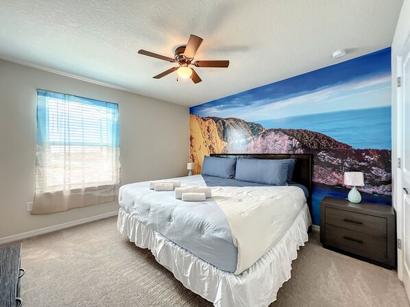 - Sleep peacefully on a king size bed with soft linens and calming ocean inspired mural behind you
- Enjoy natural light streaming through sheer curtains in a cozy and serene retreat
- Ceiling fan adds a gentle breeze to this beach themed escape

