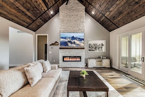 Welcome to the heart of the home - an open concept living room designed for gathering and relaxation. With an 85-inch TV and plenty of comfortable seating for the entire group, this space is p