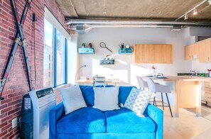 Charming vintage-style living room with a simulated brick accent wall and large windows showcasing stunning 8th-floor city views