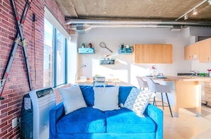 Charming vintage-style living room with a simulated brick accent wall and large windows showcasing stunning 8th-floor city views