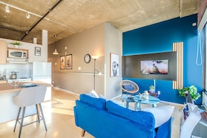 Charming vintage-style living room with a simulated brick accent wall and large windows showcasing stunning 8th-floor city views