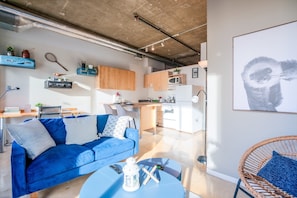 Charming vintage-style living room with a simulated brick accent wall and large windows showcasing stunning 8th-floor city views