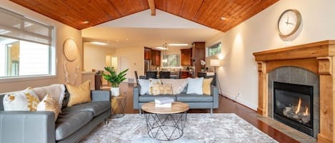 The living room has two large windows and an open concept. The fireplace is a focal point of the room and the high ceilings make it feel warm and cozy.