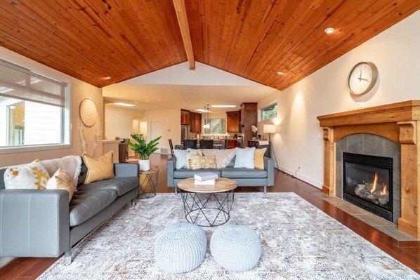 The living room has two large windows and an open concept. The fireplace is a focal point of the room and the high ceilings make it feel warm and cozy.