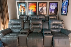Enjoy a cinematic experience in your private home theater with plush recliners and iconic movie posters.