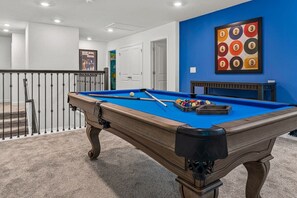 Enjoy a game night in this vibrant and stylish private game room with a pool table and colorful decor.
