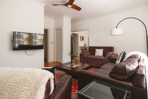 Living room with leather couch, leather loveseat, & pullout couch. Mounted smart TV